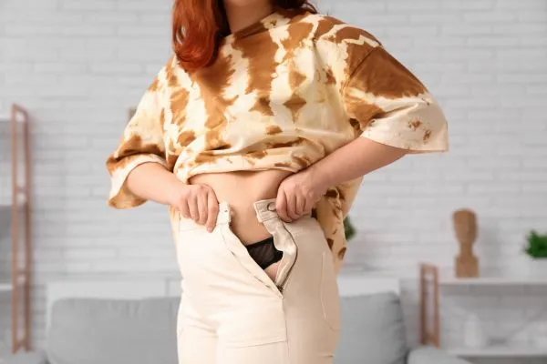Image of woman trying to do her trousers up after pregnancy weight gain Hatfield